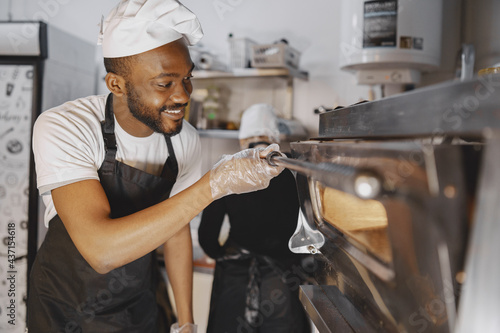 African merican man baking pizza at commercial kitchen photo