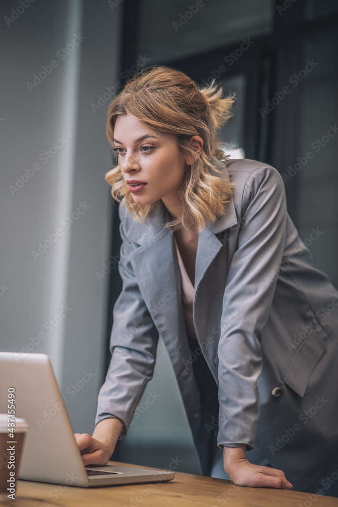 Woman standing in front of open laptop in office Woman standing in front of open laptop in office