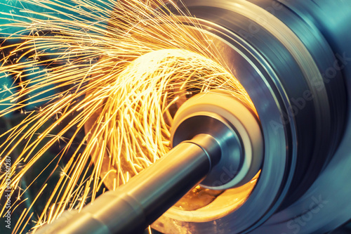 Internal grinding of a cylindrical part with an abrasive wheel on a machine, sparks fly in different directions. Metal machining. photo