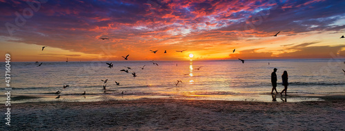 A beautiful sunset and silhouette of couple walking along the shoreline on the sand, taken at Clearwater Beach, Florida