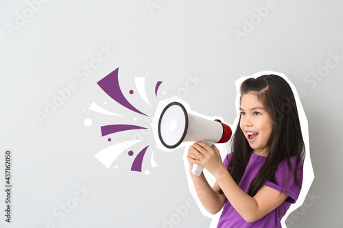 Cute little girl with megaphone on light background