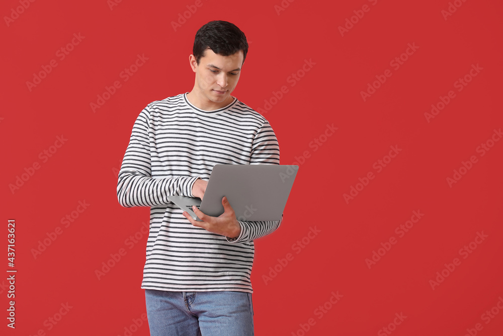 Handsome young man using laptop on color background Handsome young man using laptop on color background