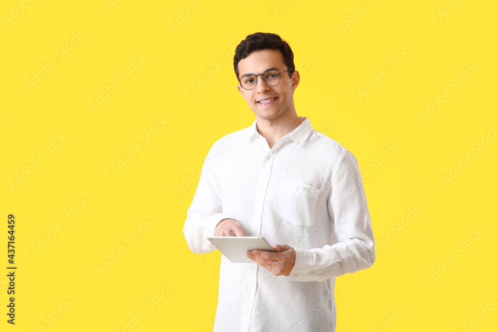 Handsome young man with tablet computer on yellow background Handsome young man with tablet computer on yellow background