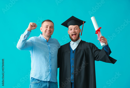 Happy male graduation student with his father on color background