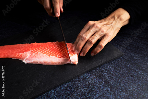 Female cook preparing a piece of Salmon to make sushi. Asian food concept