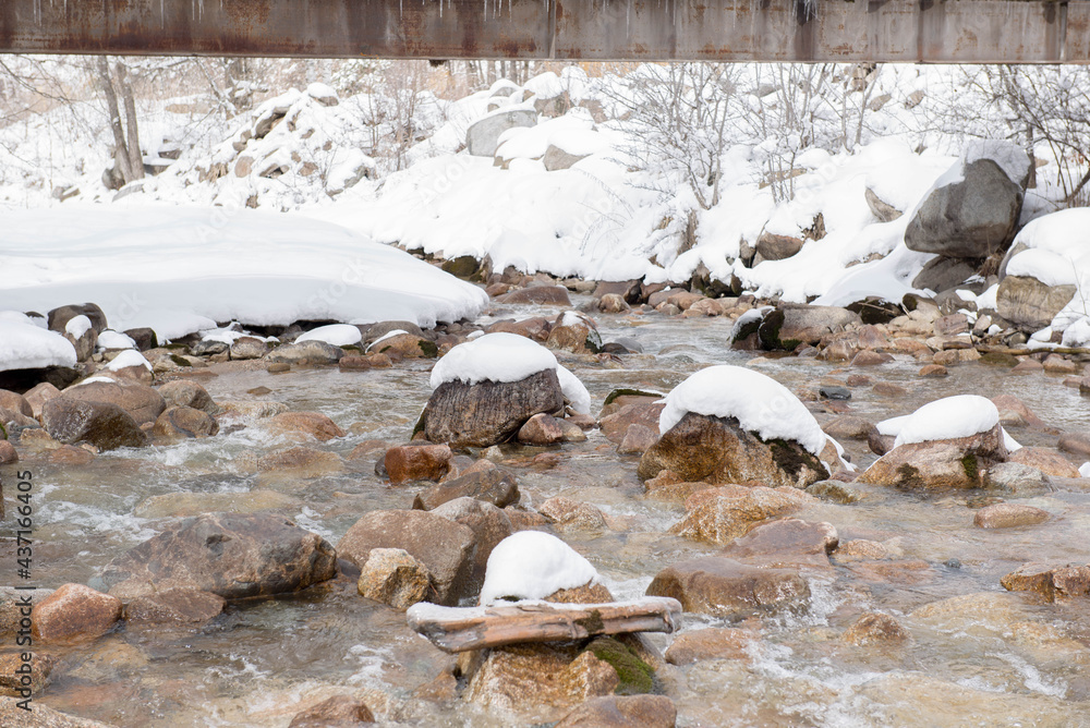 mountain river with stones in the snow