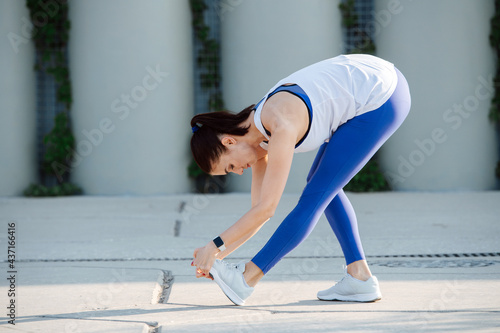 Fototapeta Naklejka Na Ścianę i Meble -  Good looking woman stretching on a concrete paving, doing forward bends