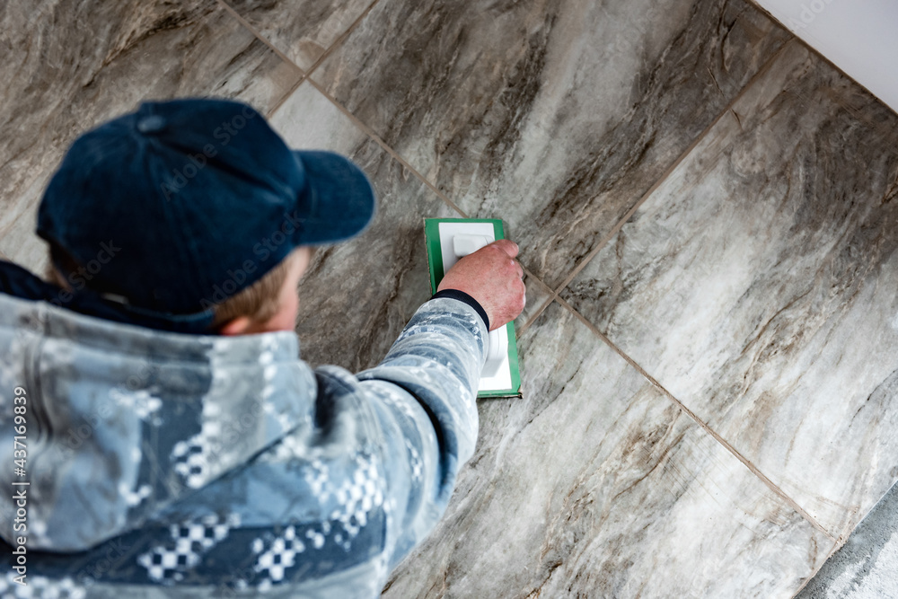 Grouting ceramic tiles. Tilers filling the space between tiles using a rubber trowel. Grouting ceramic tiles. Tilers filling the space between tiles using a rubber trowel.