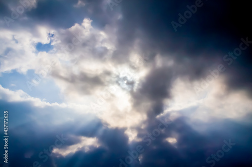 the sun's rays make their way through large dark clouds