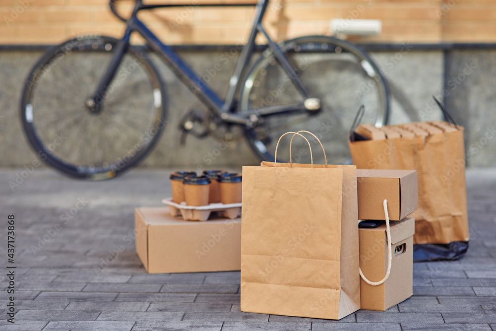 Various packages with food, pizza boxes and four coffee cups standing on the street road Various packages with food, pizza boxes and four coffee cups standing on the street road