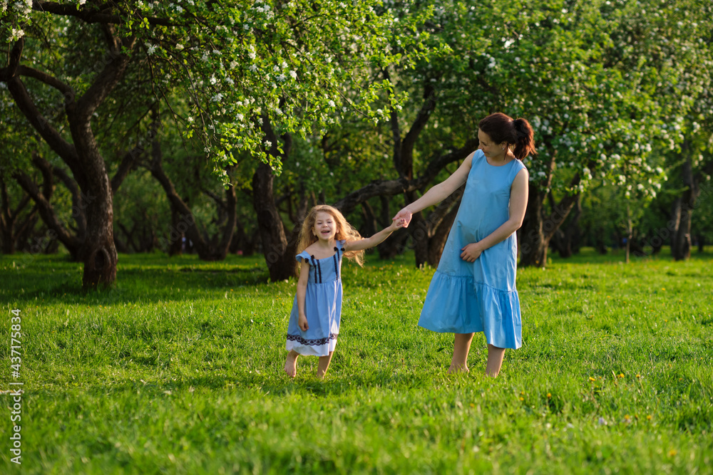 Fototapeta premium nature scene with family outdoor lifestyle. Mother and little daughter playing together in a park. Happy family concept. Happiness and harmony in family life.