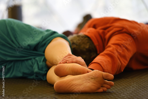 Couple lying down in group workshop connected by bare hands and bare feet