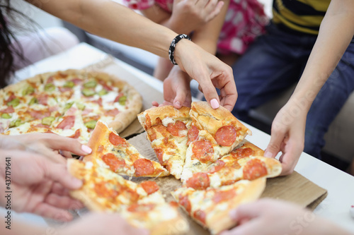 Hands of children and parents taking slice of pizza closeup