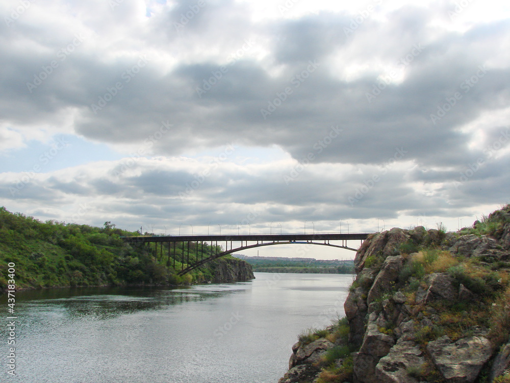 Bottom view of the power and grandeur of the arch bridge against the background of heavy gray clouds.
