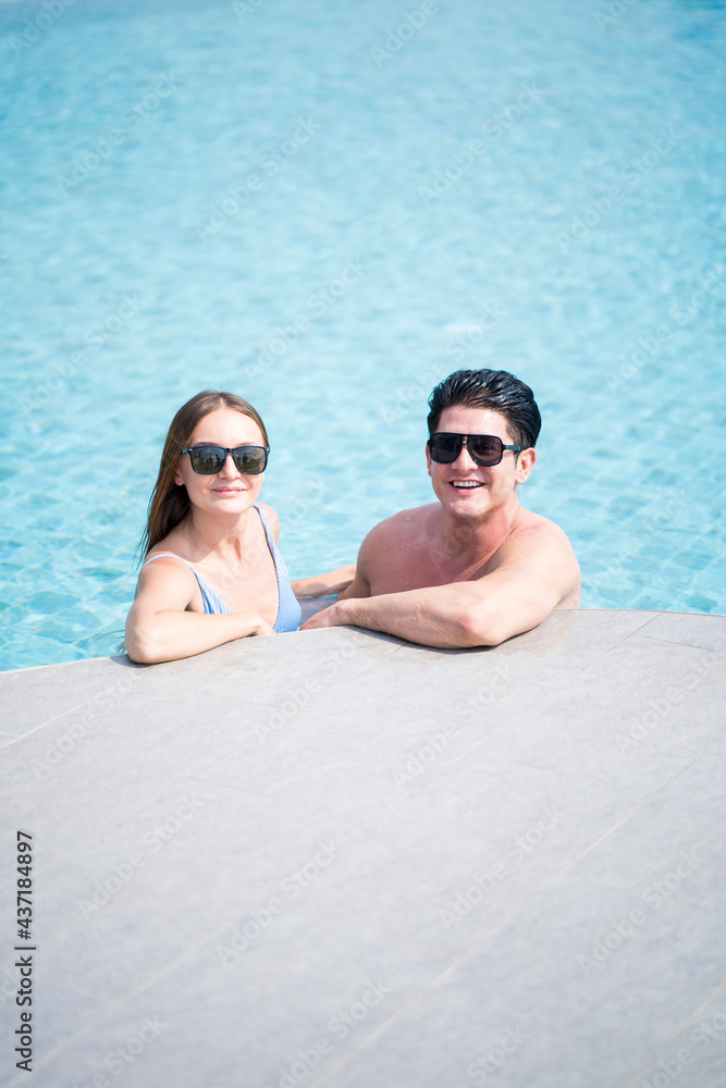 Man and woman in a swimming pool. Young couple embracing in the pool. couple looking at the camera. Man and woman in a swimming pool. Young couple embracing in the pool. couple looking at the camera.