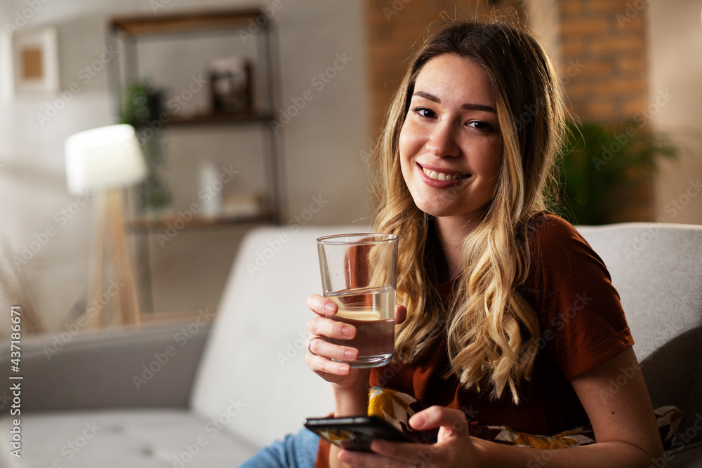 Beautiful young girl using the phone while drinkinng water. Portrait of smiling girl typing a message. Beautiful young girl using the phone while drinkinng water. Portrait of smiling girl typing a message.