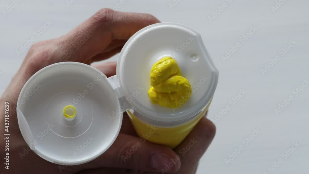 An Artist Squeezes Out Some yellow Paint From A Tube Of Acrylic Paint. Close up shot artistic movement, making ready to paintbrush creative in studio. An Artist Squeezes Out Some yellow Paint From A Tube Of Acrylic Paint. Close up shot artistic movement, making ready to paintbrush creative in studio.
