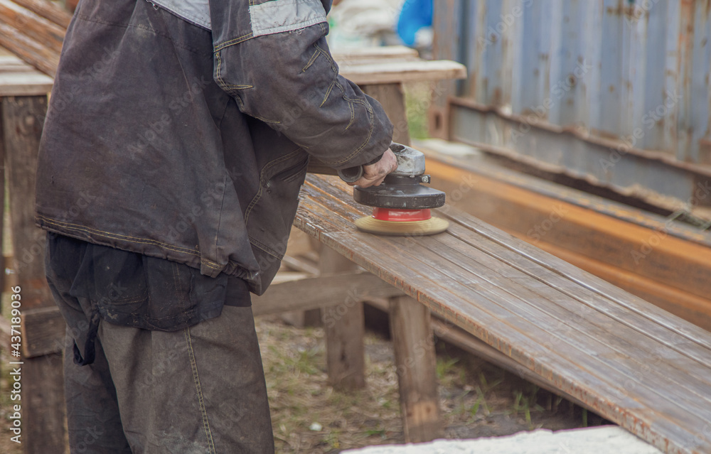 A worker grinds metal at a construction site. A worker grinds metal at a construction site.