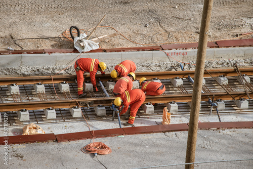 Tel Aviv, Israel - May 20 2021: Construction Workers with Orange overalls. Light rail tracks. blue collar worker. Concept Collaboration teamwork. Trucks, concrete mixer, bulldozer. High quality photo