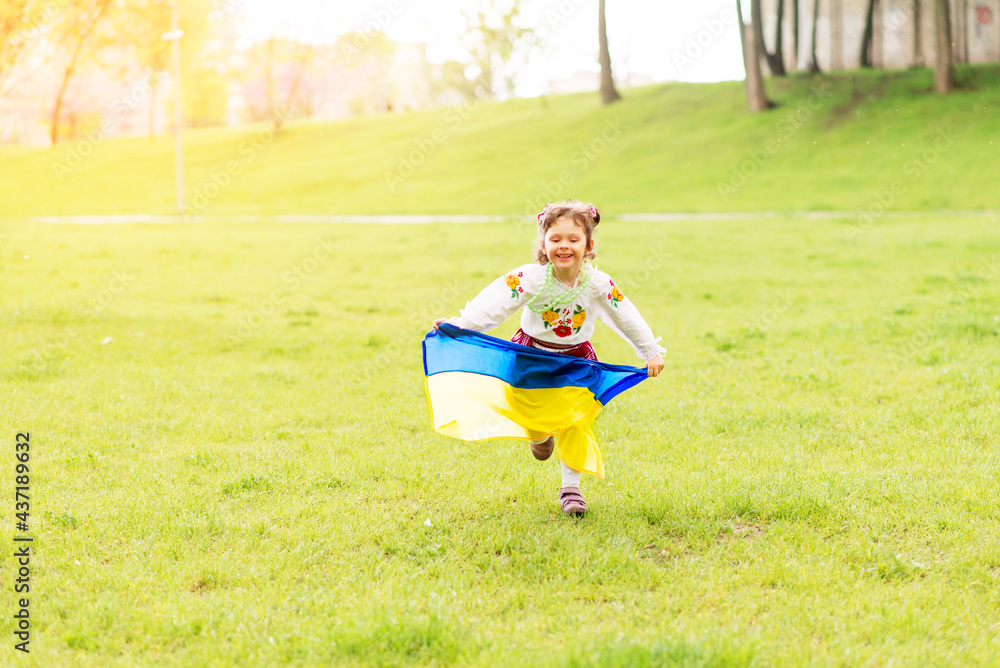 Fototapeta premium Girl with the flag of Ukraine. She is dressed in an embroidered shirt and a wreath on her head - Ukrainian national dress. August 24 - Independence Day of Ukraine.