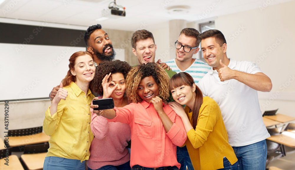 diversity, education and school concept - group of smiling international university students and teacher taking selfie with smartphone over lecture hall on background diversity, education and school concept - group of smiling international university students and teacher taking selfie with smartphone over lecture hall on background