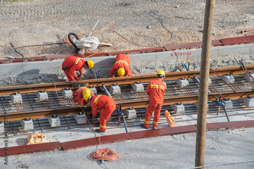 Tel Aviv, Israel - May 20 2021: Construction Workers with Orange overalls. Light rail tracks. blue collar worker. Concept Collaboration teamwork. Trucks, concrete mixer, bulldozer. High quality photo