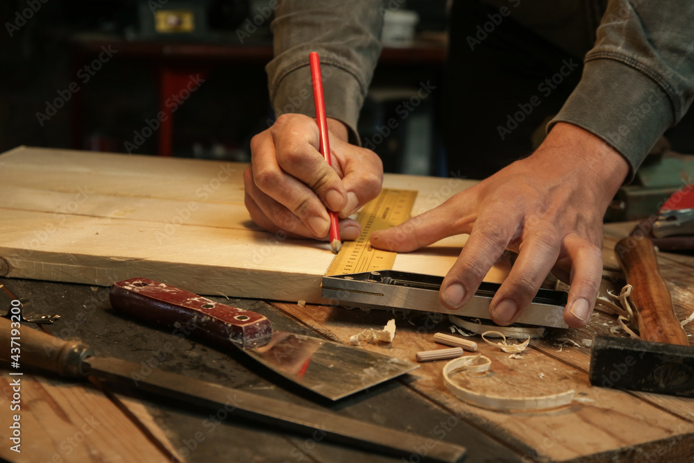 Carpenter measuring and marking wood with speed square measure tool in workshop Carpenter measuring and marking wood with speed square measure tool in workshop