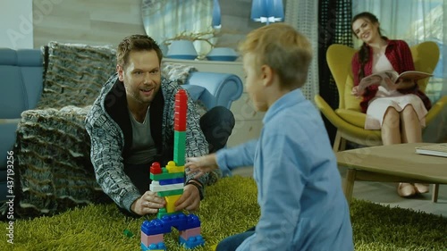 A happy young family. Dad and mom play with their sons in their apartment.