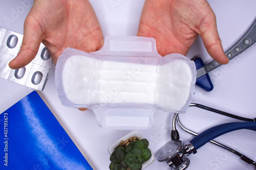 The gynecologist or hygiene doctor demonstrates the opened feminine hygiene pad during the consultation. Concept photo of women using sanitary hygiene supplies or products during menstruation top view photo