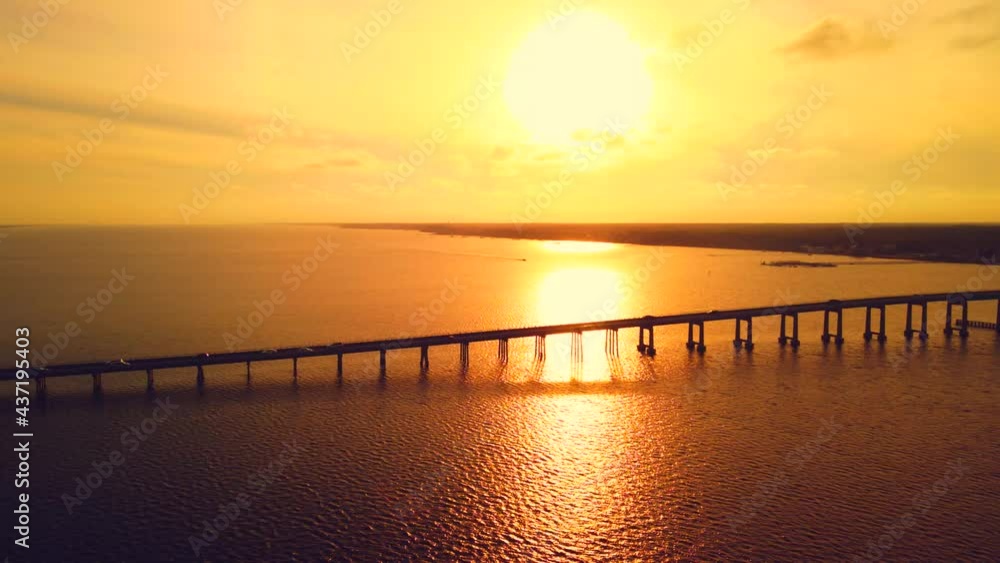 A beautiful bridge silhouettes a golden sunset as cars zoom by in this magical aerial timelapse. A beautiful bridge silhouettes a golden sunset as cars zoom by in this magical aerial timelapse.
