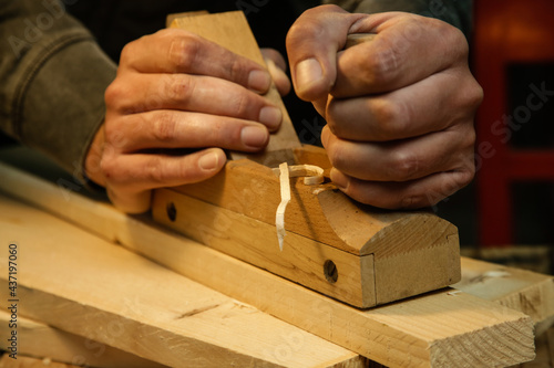Carpenter planing wood in workshop with a hand planer