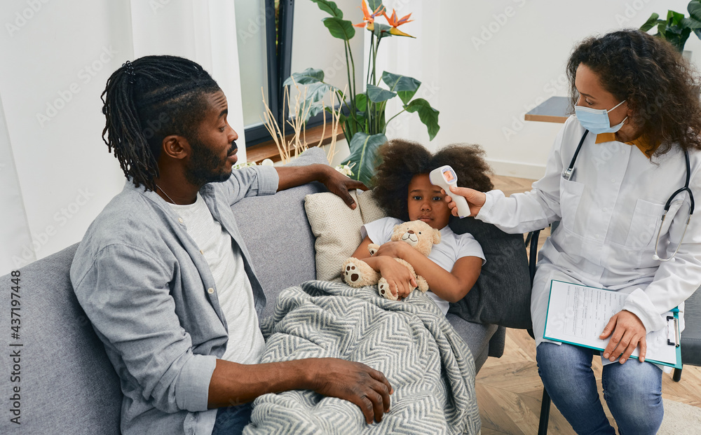 House call doctors. Pediatrician measures temperature of a little girl
