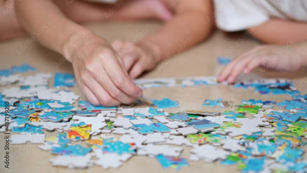 Mother and son lying on the floor doing jigsaw puzzles game. A boy finding a piece of puzzle and put it together. Kid category a part of puzzle by color. Learning and education concept. Mother and son lying on the floor doing jigsaw puzzles game. A boy finding a piece of puzzle and put it together. Kid category a part of puzzle by color. Learning and education concept.