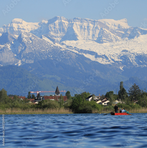 Blue water of Lake Pfaffikon, Pfaeffikon. Reed and church. Snow covered peaks. photo