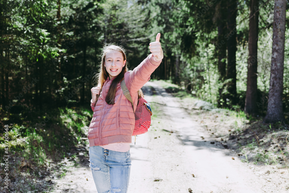 One cheerful traveler teen girl, showing thumb up.teenager hand gesturing thumbs up in a park.Summer sunny day. One cheerful traveler teen girl, showing thumb up.teenager hand gesturing thumbs up in a park.Summer sunny day.