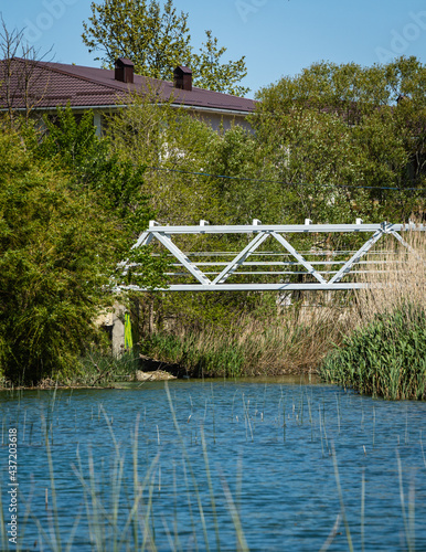 Metal pedestrian bridge over mountain river Teshebs in Arkhipo-Osipovka. Close-up. There are small mini-hotels on right bank of river. Mouth of Teshebs river. Gelendzhik, Russia - May 15, 2021 photo