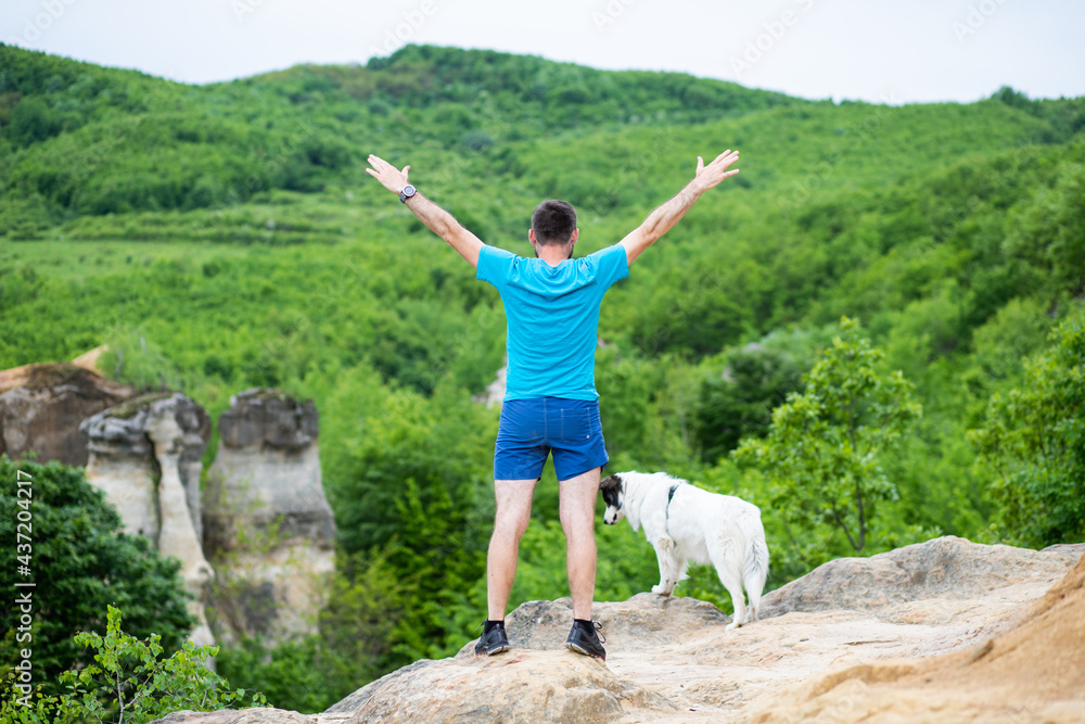 man with his dog sitting on a rock enjoying nature