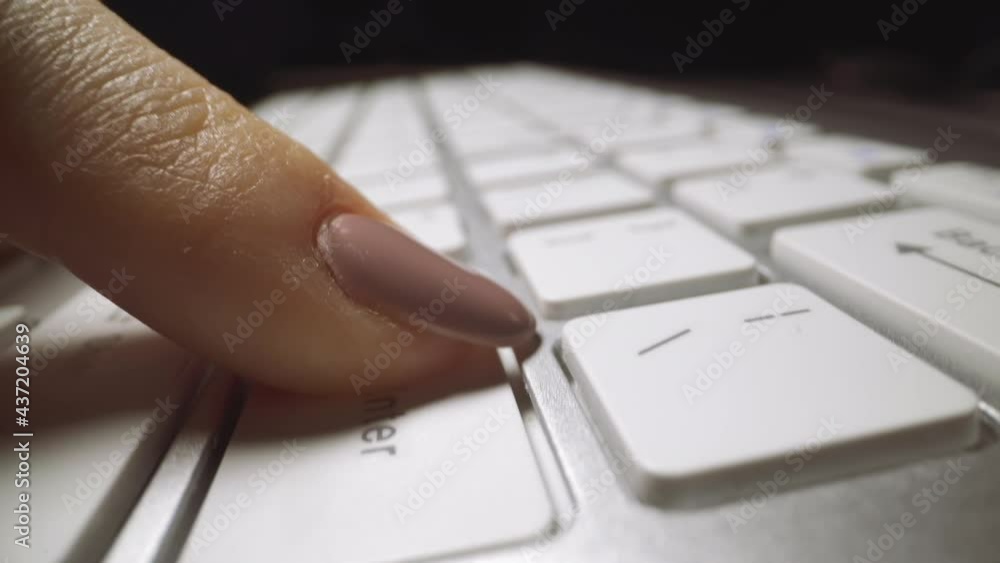 Nervous woman finger with pink nail polish presses Enter key hitting on keyboard of hung computer on black background extreme closeup Nervous woman finger with pink nail polish presses Enter key hitting on keyboard of hung computer on black background extreme closeup