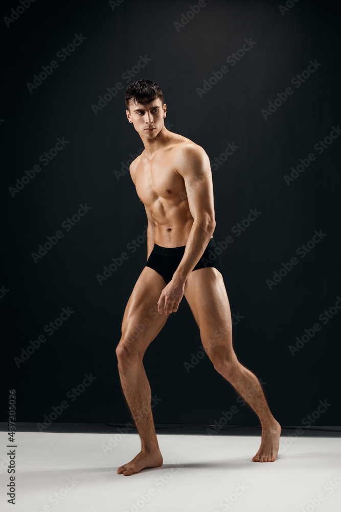 man with muscular naked body in black panties on a dark background