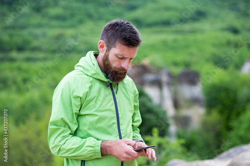 man trekking checking map on smartphone in summer scenery