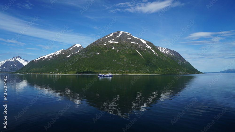 The lush snow-capped and icy mountain opposite Tromso, combined with the clear blue sky and its reflection in the sea water, is spectacular, Norway