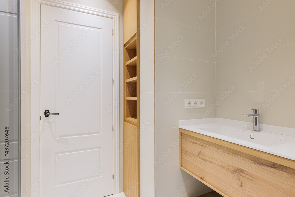 Modern bathroom with wooden base for white sinks. Radiator for warm water procedures in winter. Shower zone with glass door. Bathroom decorated with light tiles Modern bathroom with wooden base for white sinks. Radiator for warm water procedures in winter. Shower zone with glass door. Bathroom decorated with light tiles