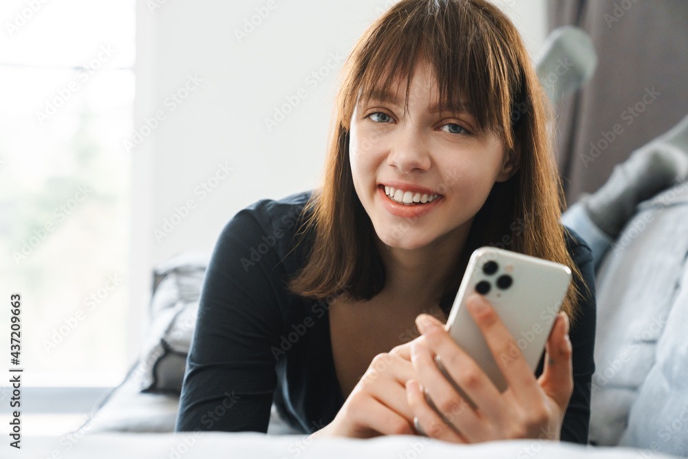 Smiling young woman holding mobile phone texting Smiling young woman holding mobile phone texting