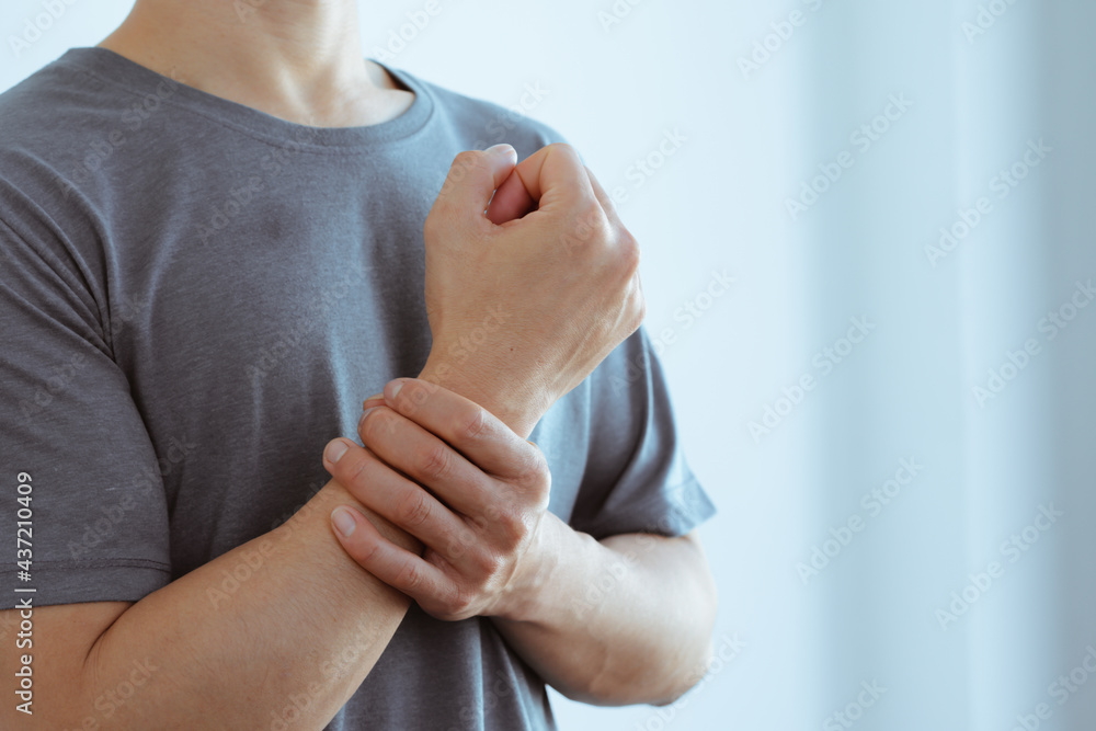 Φωτογραφία male arms holding his painful wrist caused by prolonged work on the computer, laptop,neurological disease concept