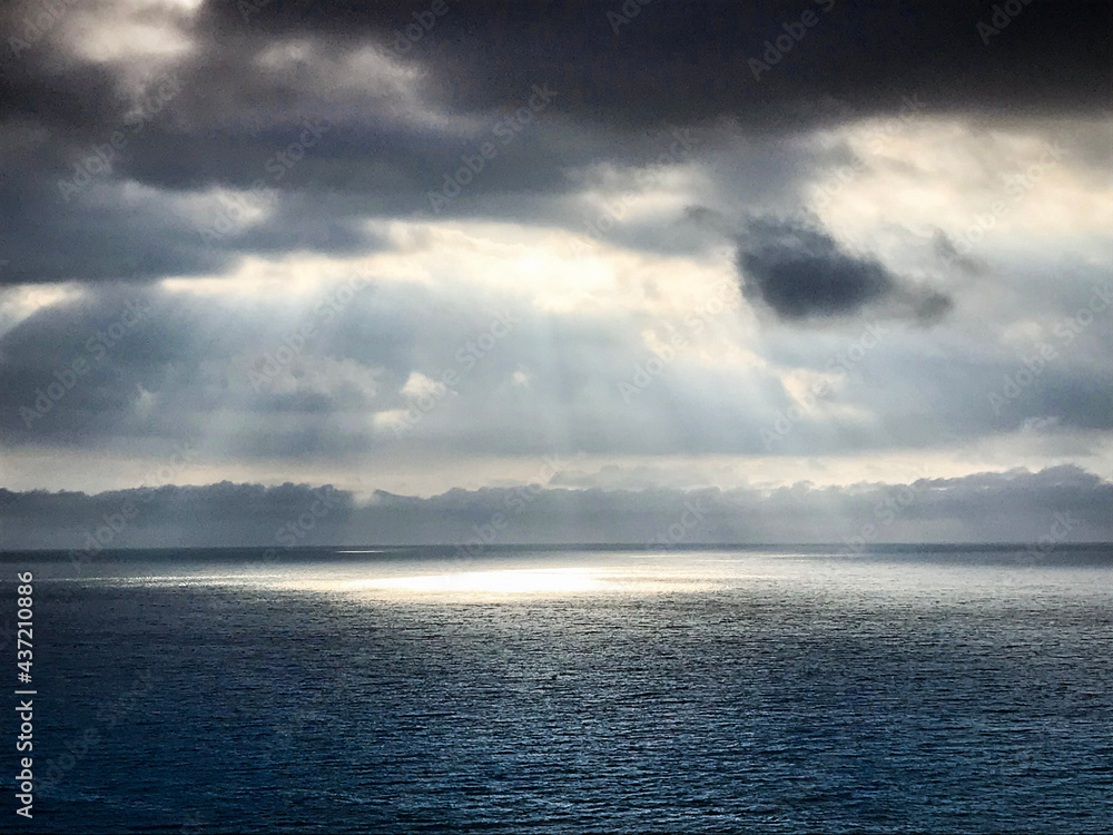 The moment when rays of light shine through the clouds onto the ocean.