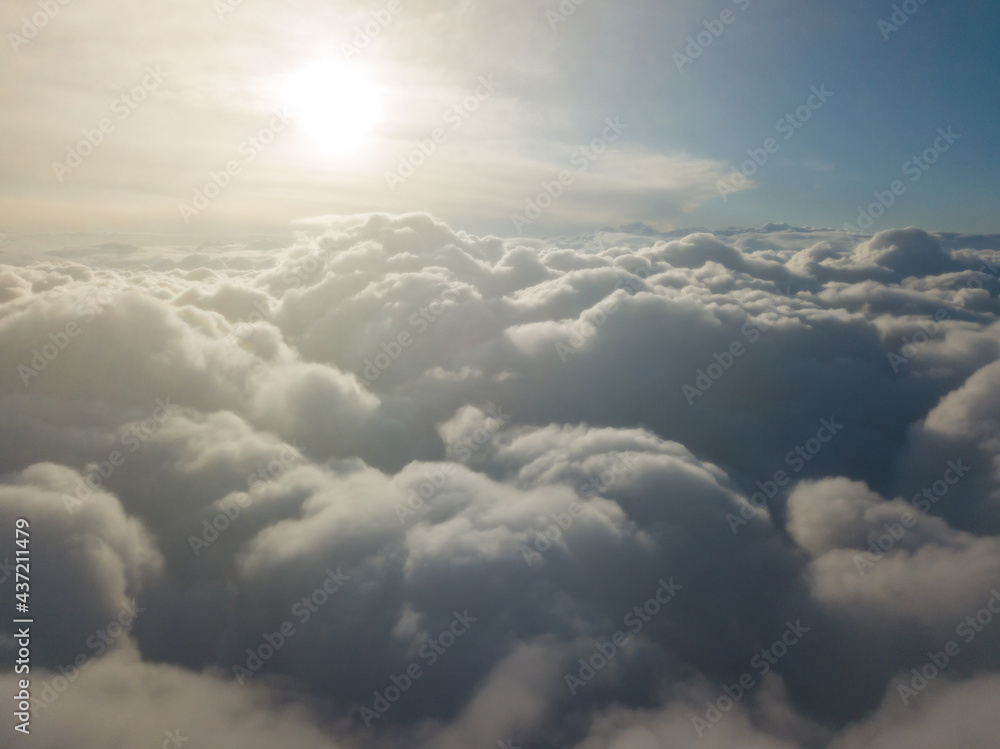 Aerial high flight above the clouds at sunrise.