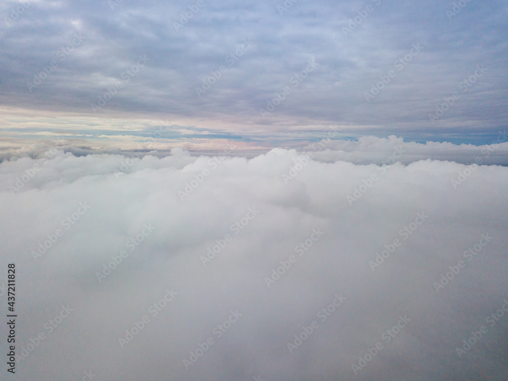 Obraz premium Aerial high flight above the clouds. The rays of the rising sun break through the clouds.