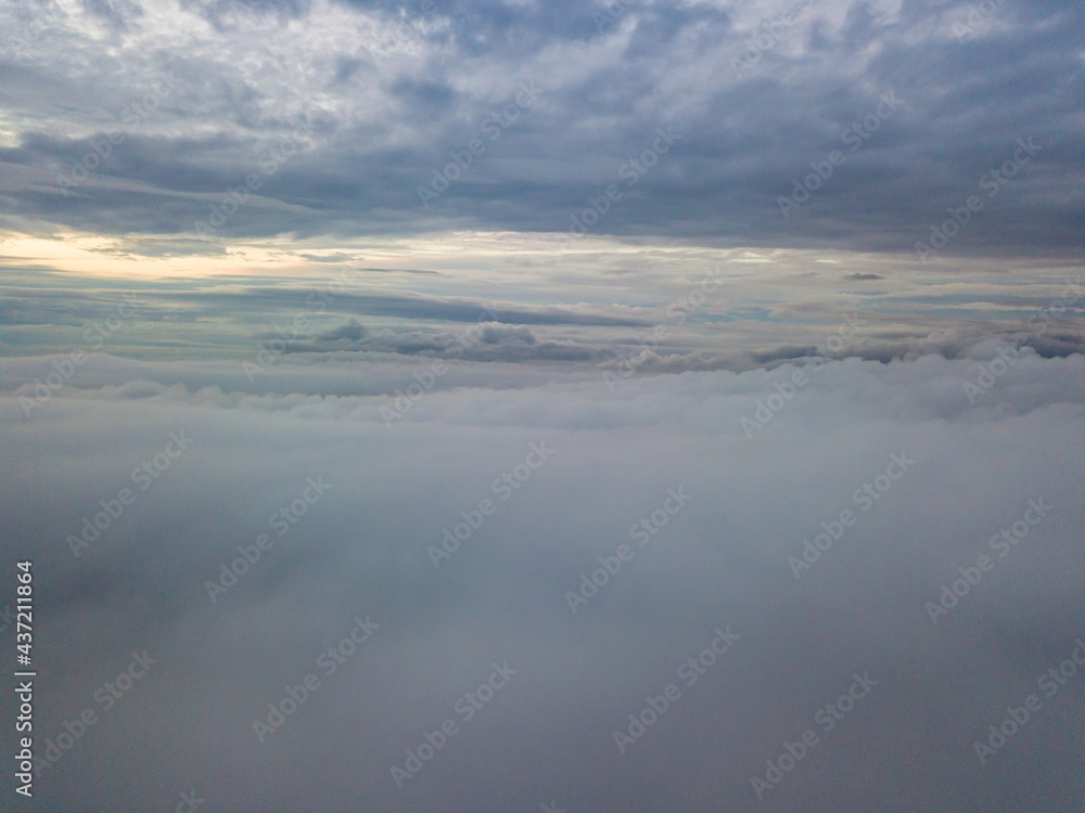 Fototapeta premium Aerial high flight above the clouds. The rays of the rising sun break through the clouds.