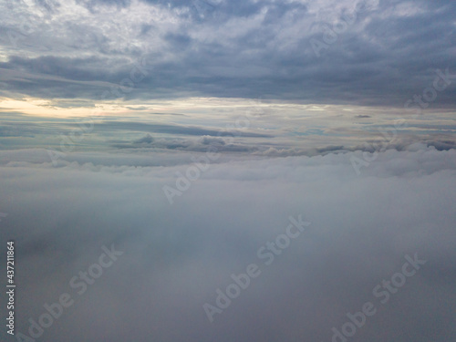 Aerial high flight above the clouds. The rays of the rising sun break through the clouds.