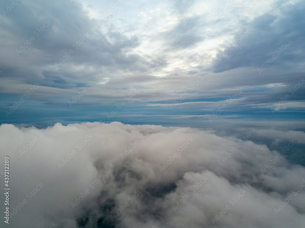 Obraz premium Aerial high flight above the clouds. The rays of the rising sun break through the clouds.